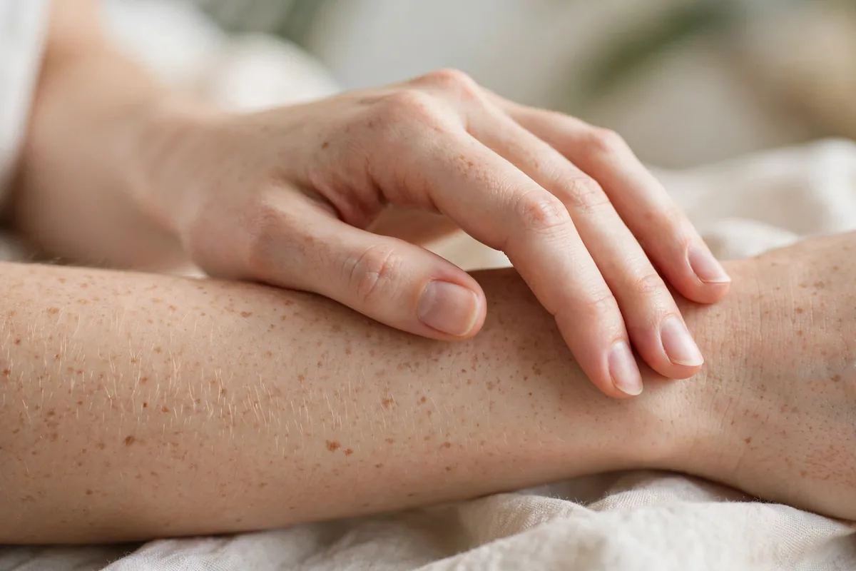 Close-up of a woman's hand gently touching her forearm